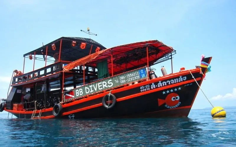 Bateau de plongée rouge et noir avec des personnes à bord en mer