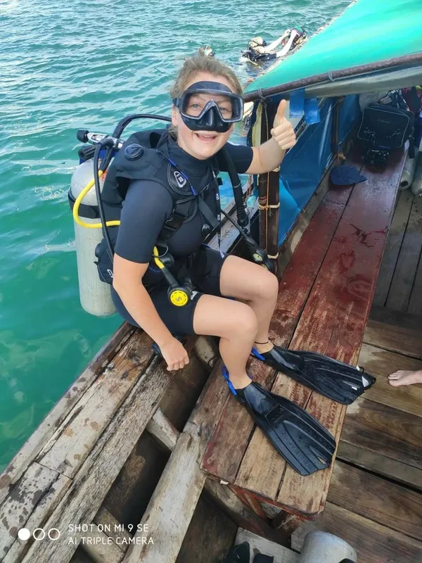 Plongeuse souriante avec son équipement sur un bateau de plongée
