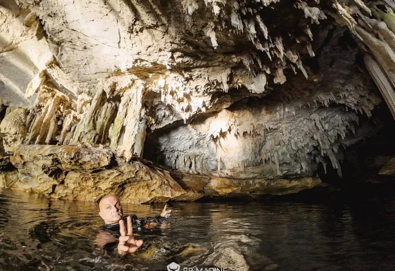 Plongeur en combinaison dans une grotte sous-marine avec stalactites
