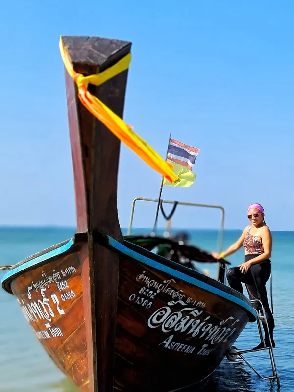Bateau de pêche traditionnel thaïlandais avec une plongeuse assise à l'avant