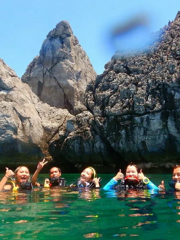 Groupe de plongeurs souriants et faisant des signes dans une eau turquoise
