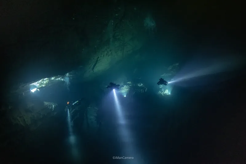 Plongeurs explorant une grotte sous-marine avec des faisceaux lumineux