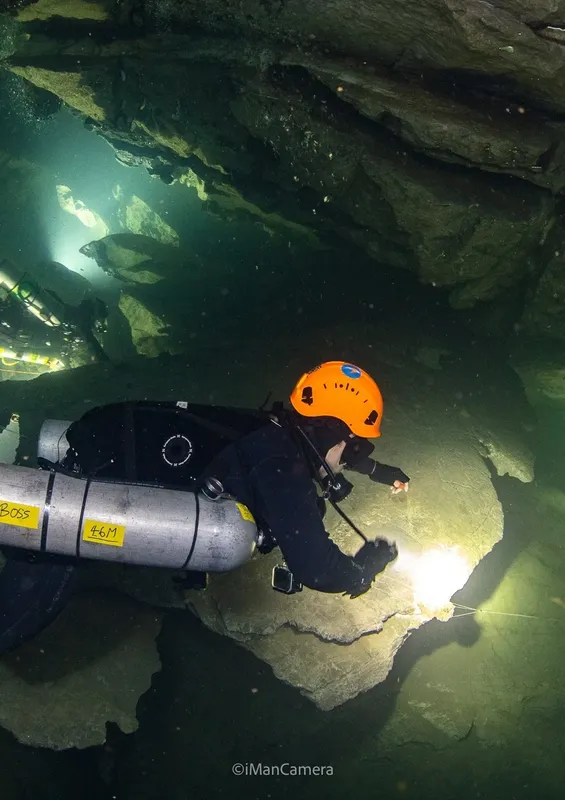 Deux plongeurs explorent une grotte sous-marine, lumière artificielle