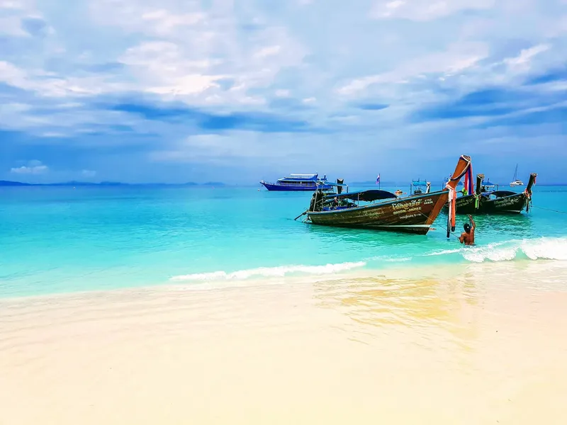 Plage de sable blanc avec bateaux traditionnels et mer turquoise