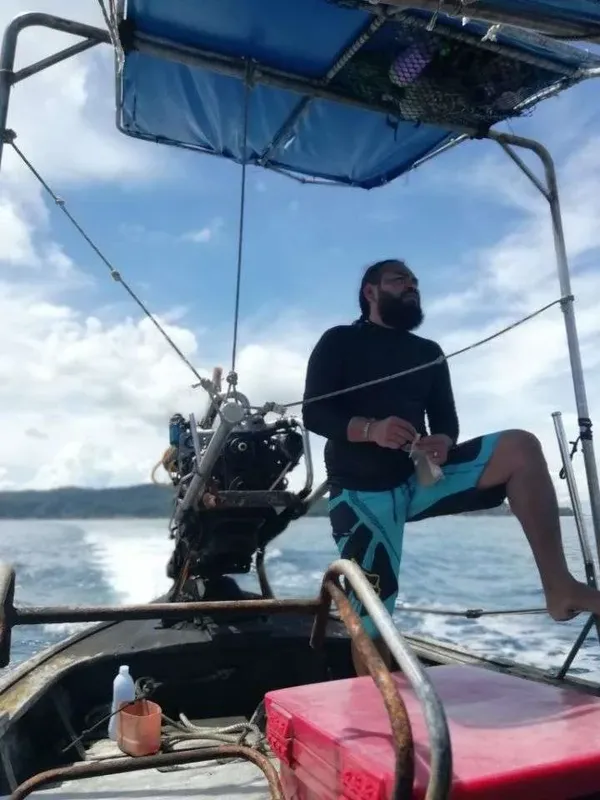 Homme barbu sur un bateau de plongée en mer, tenant un objet