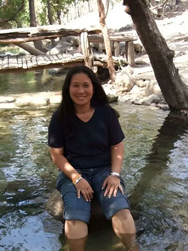 Femme souriante assise dans l'eau peu profonde au bord d'une rivière