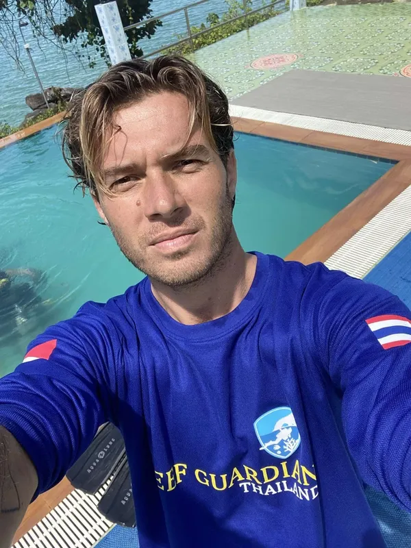 Portrait d'un homme souriant près d'une piscine avec un t-shirt bleu
