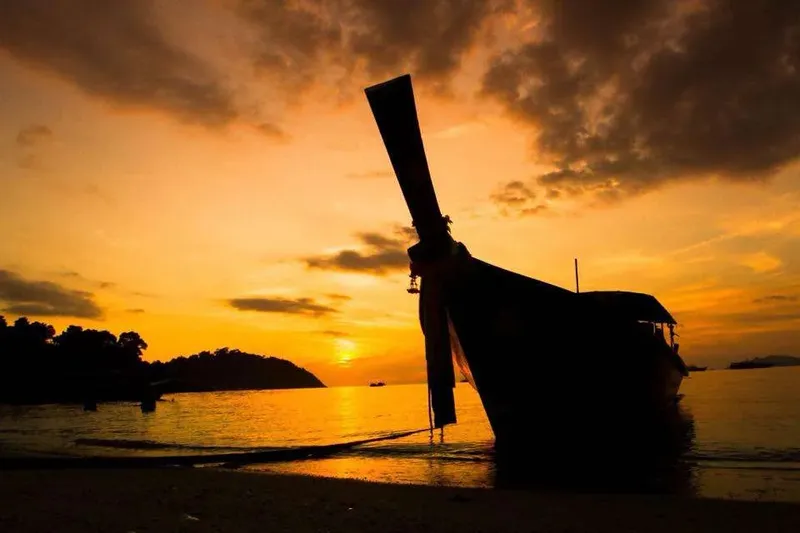 Bateau traditionnel échoué sur une plage au coucher du soleil