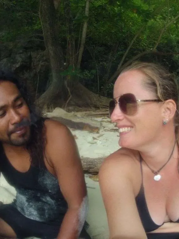 Deux personnes souriantes sur une plage de sable blanc tropical