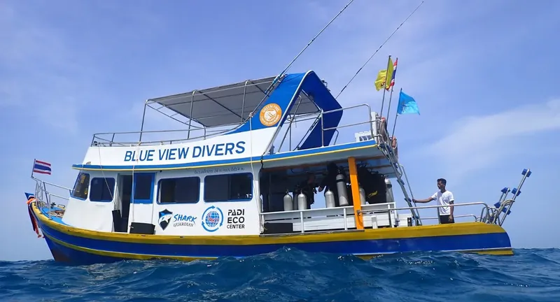 Bateau de plongée bleu et jaune avec des bouteilles et un plongeur
