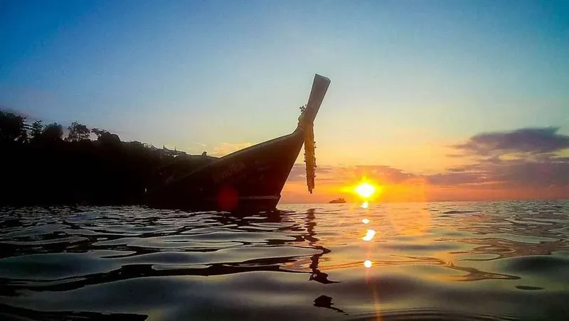 Bateau traditionnel au coucher du soleil sur une mer calme