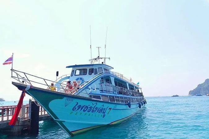 Bateau de plongée turquoise amarré à un ponton avec des passagers