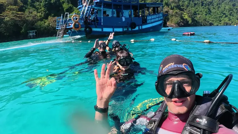 Plongeurs souriants saluent avec la main dans une eau turquoise claire