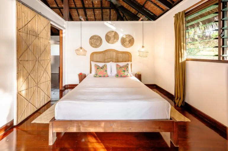 Chambre d'hôtel avec lit double, décoration en bambou et lumière naturelle