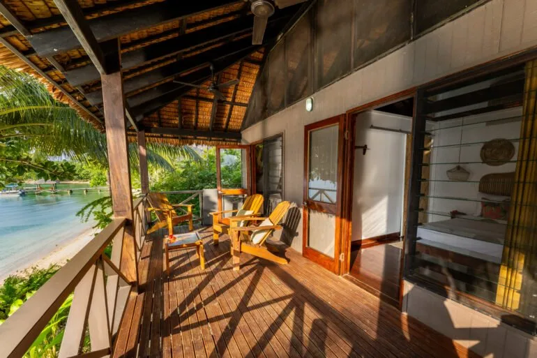 Terrasse en bois avec mobilier, vue sur la mer et végétation tropicale