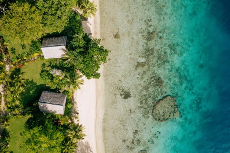 Vue aérienne d'une plage tropicale avec des bâtiments et végétation luxuriante