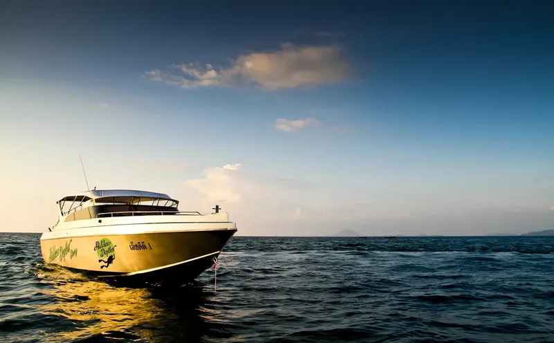 Bateau de plongée jaune sur l'eau calme sous un ciel bleu nuageux