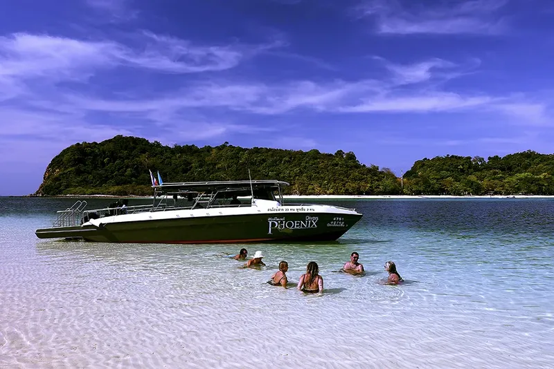 Plage de sable blanc avec des personnes et un bateau de plongée