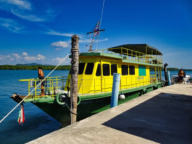 Bateau de plongée jaune et vert amarré à un ponton ensoleillé