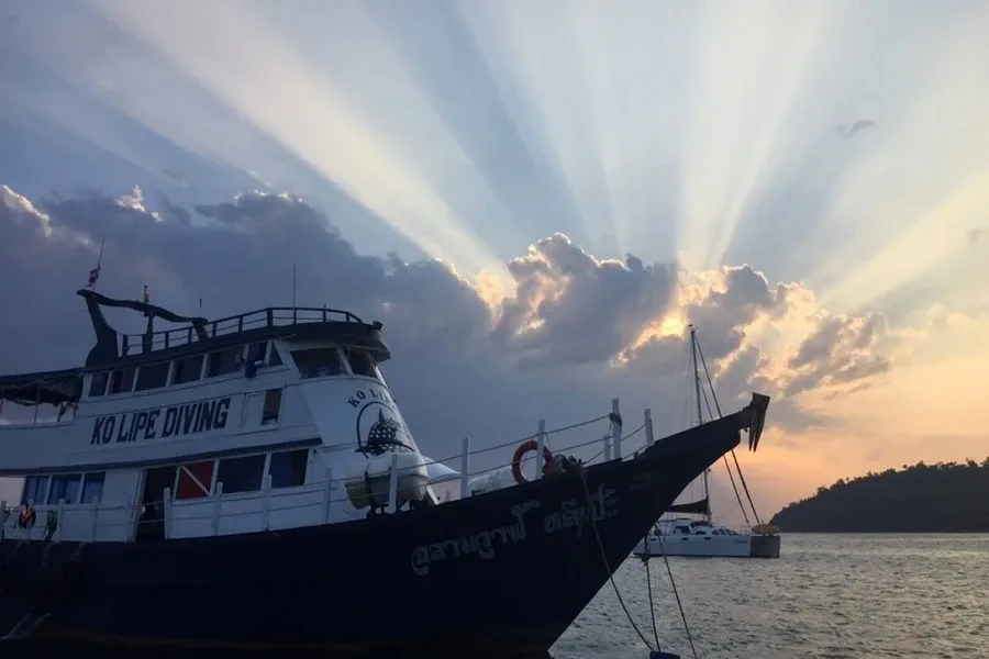Bateau de plongée amarré au coucher du soleil avec rayons lumineux