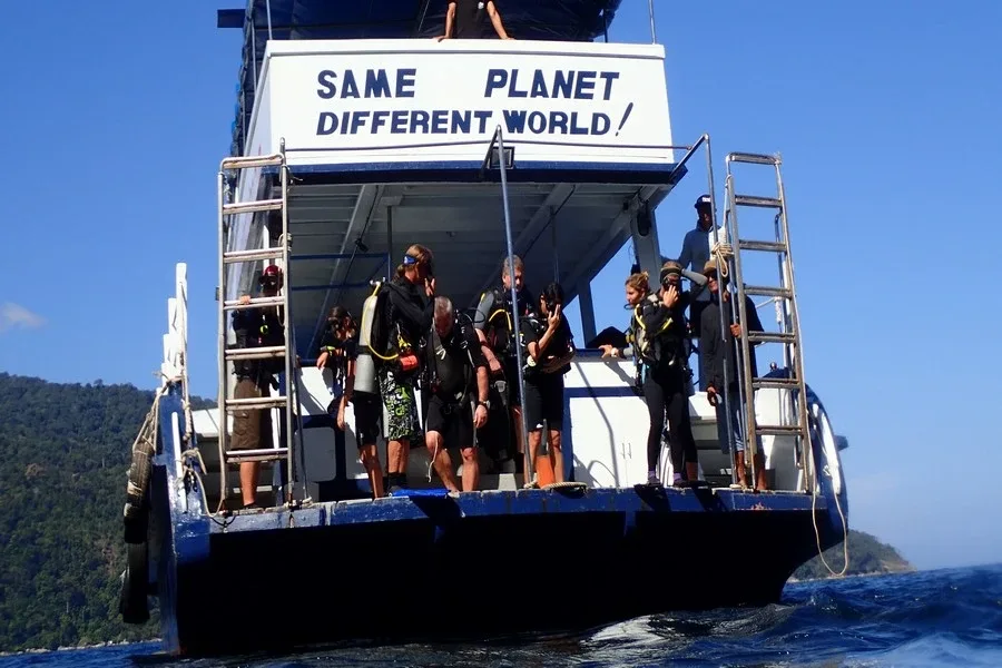 Plongeurs équipés se préparent à bord d'un bateau de plongée bleu