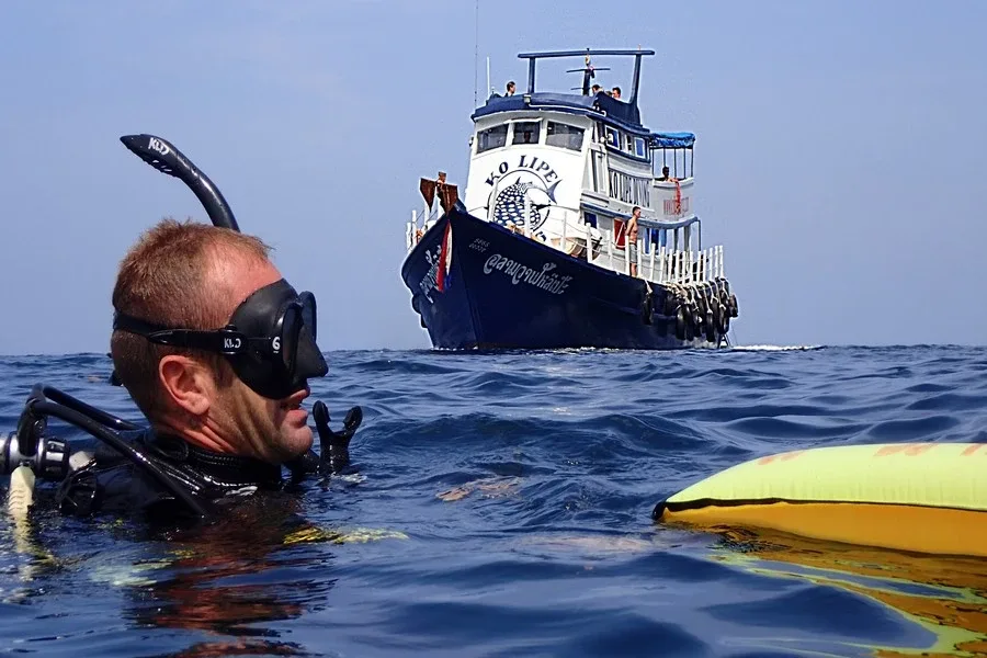 Plongeur avec tuba et masque, regardant un bateau en mer
