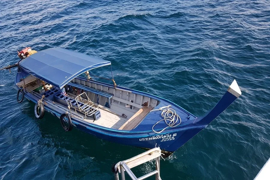 Petit bateau de pêche longiligne bleu et blanc sur mer calme