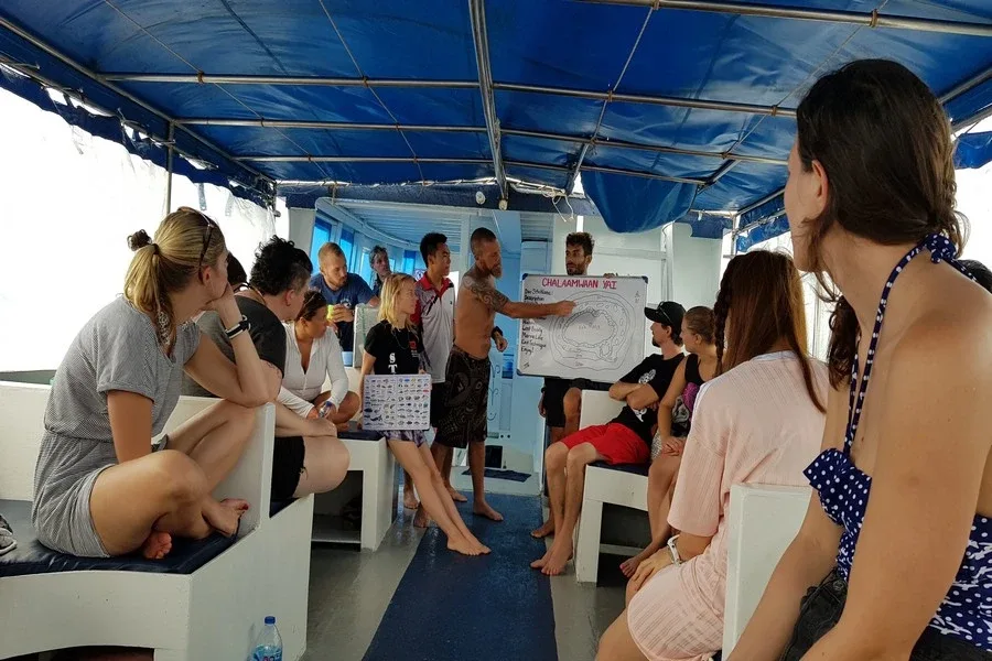 Groupe de personnes sur un bateau, un instructeur explique avec un tableau