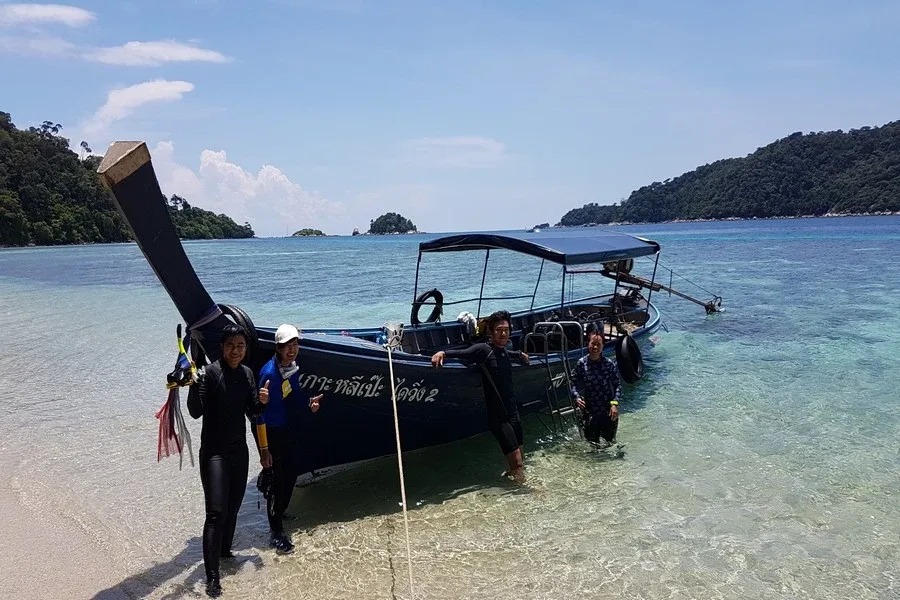 Plongée : des personnes montent à bord d'un longtail boat sur une plage