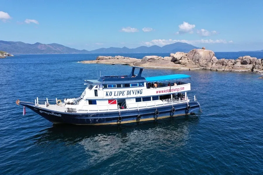 Bateau de plongée blanc et bleu navigue sur une mer turquoise