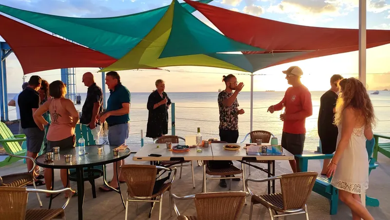 Groupe de personnes discutant sur une terrasse au coucher du soleil