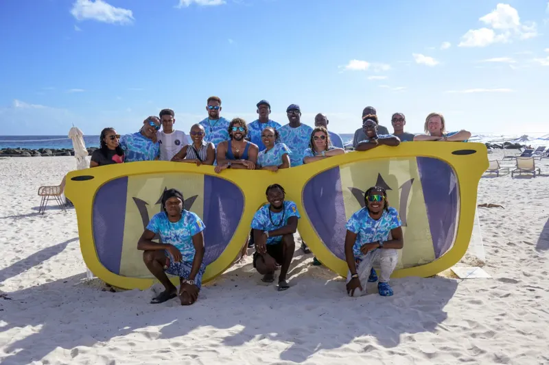 Groupe de personnes souriantes posant devant de grandes lunettes de soleil