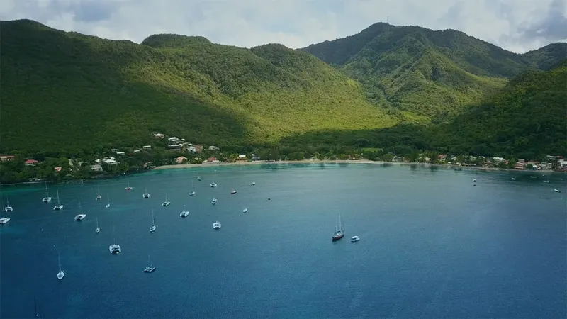 Vue aérienne d'une baie avec des bateaux amarrés et des collines verdoyantes