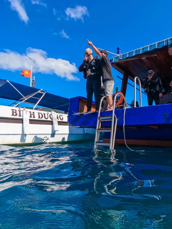 Plongeurs sur un bateau, un instructeur pointe vers l'avant