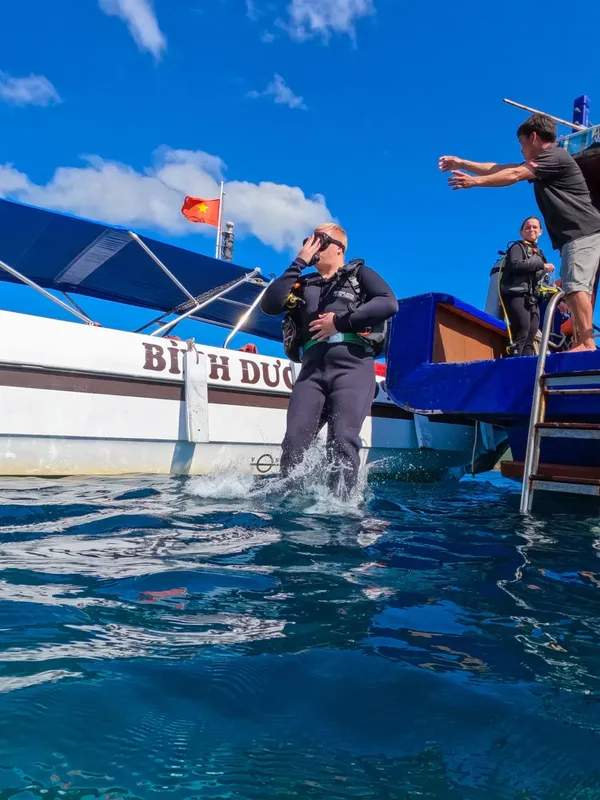 Plongeur sortant de l'eau sur un bateau avec aide d'un autre