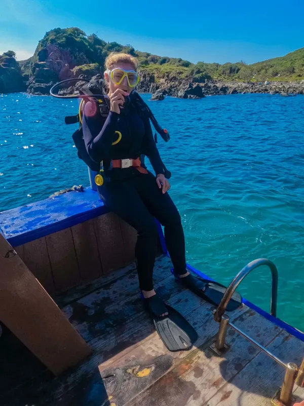 Plongeuse en combinaison assise sur un bateau avec son équipement