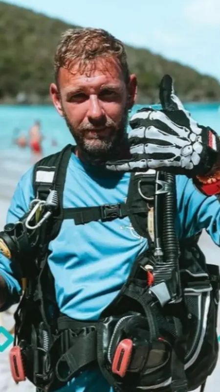 Plongeur souriant avec équipement complet sur une plage ensoleillée