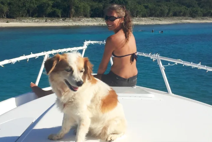 Femme et chien souriants sur la proue d'un bateau en mer