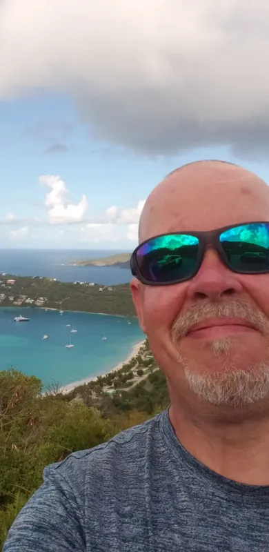 Homme souriant avec lunettes de soleil, vue sur mer et bateaux