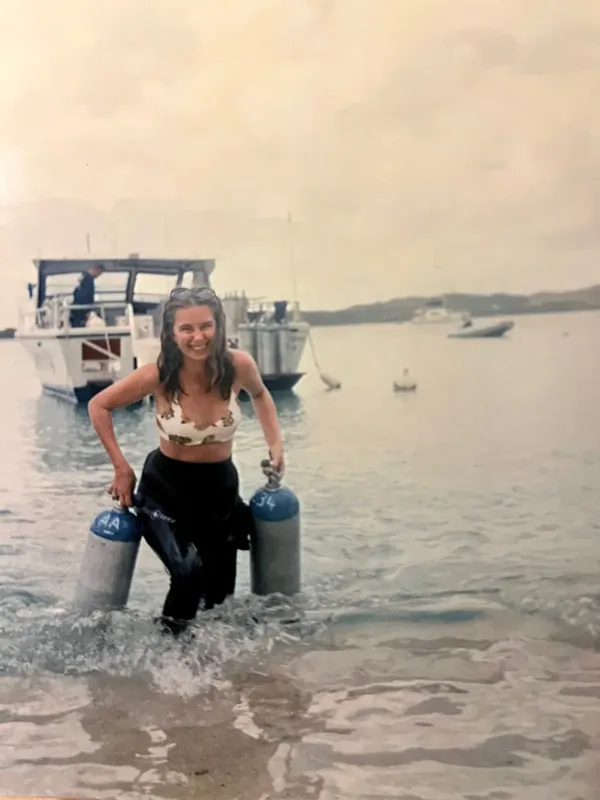 Plongeuse souriante sortant de l'eau avec deux bouteilles