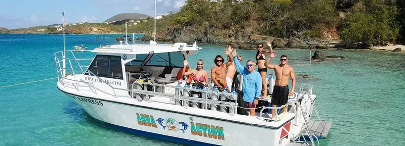 Groupe de plongeurs souriants sur un bateau blanc en mer turquoise