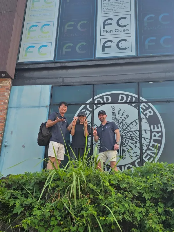 Quatre personnes souriantes posent devant la facade d'un centre de plongée
