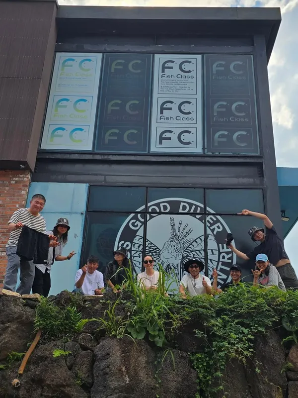 Groupe de personnes souriantes devant un bâtiment avec des logos