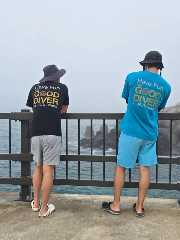 Deux plongeurs regardent l'eau depuis un ponton en béton