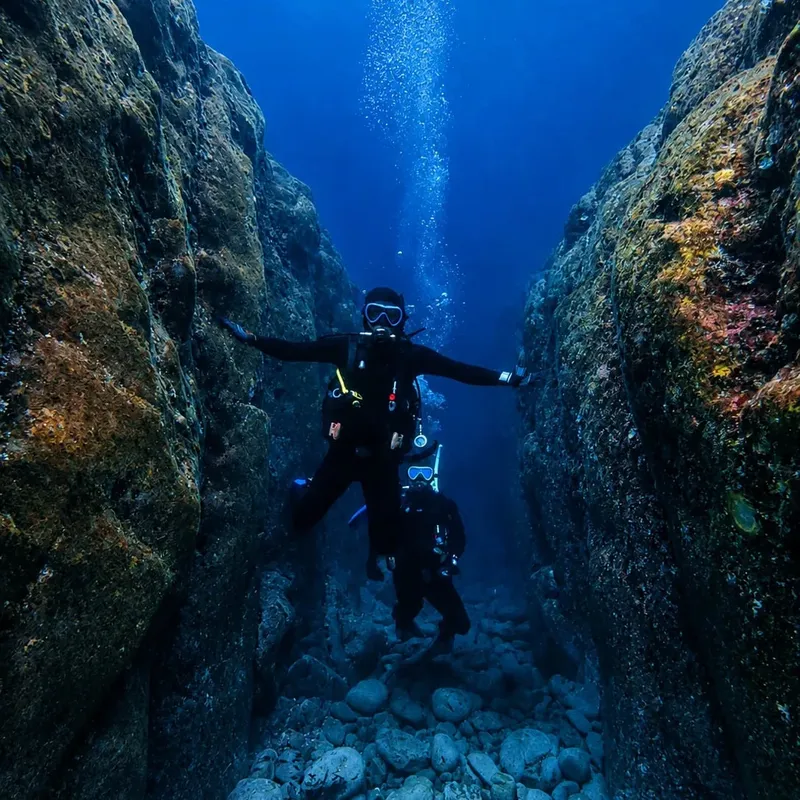 Deux plongeurs explorent une fissure rocheuse sous-marine en toute sécurité