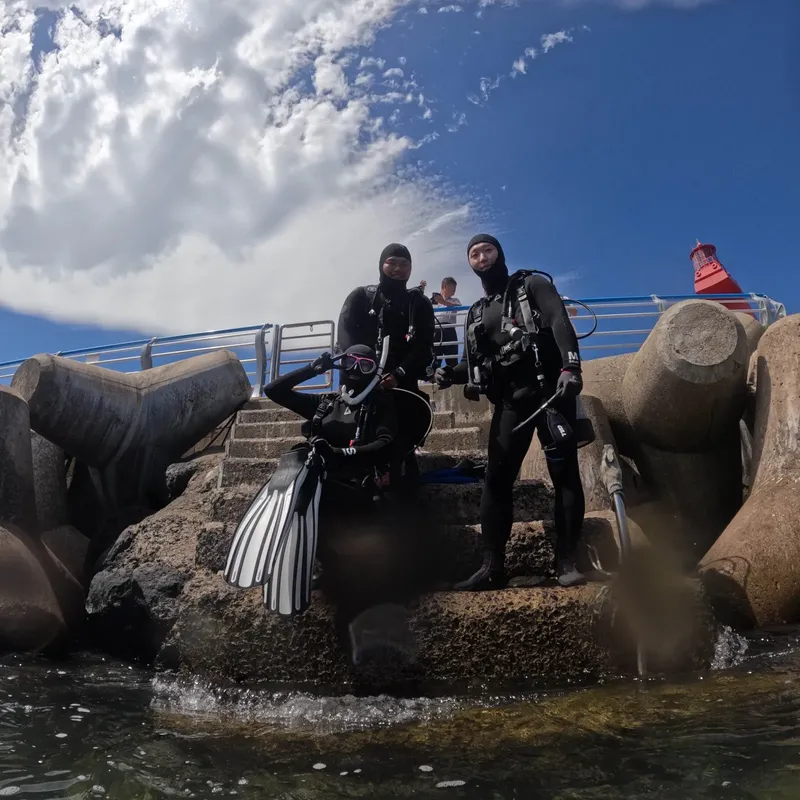 Trois plongeurs en combinaison, équipés, se préparent pour une immersion
