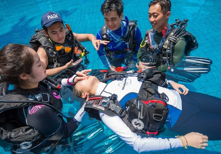 Quatre personnes équipées pour la plongée en piscine, formation