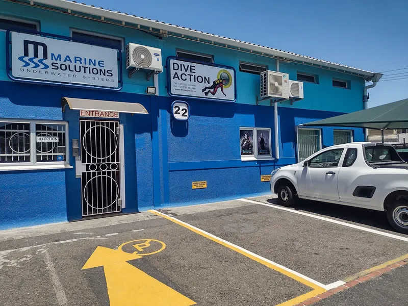 Façade bleue d'un centre de plongée avec entrée et place de parking