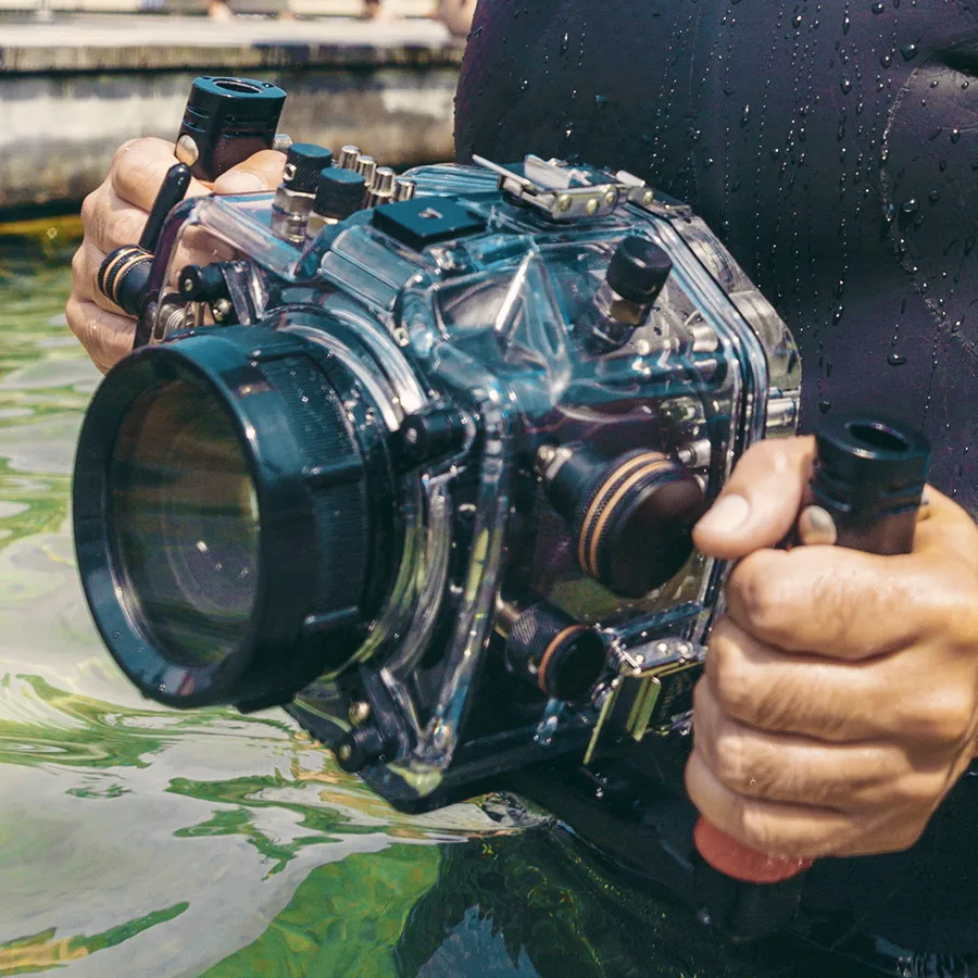 Mains tenant un appareil photo sous-marin transparent avec des reflets