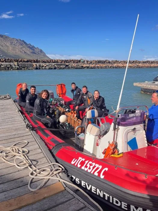 Groupe de plongeurs souriants à bord d'un bateau rouge amarré